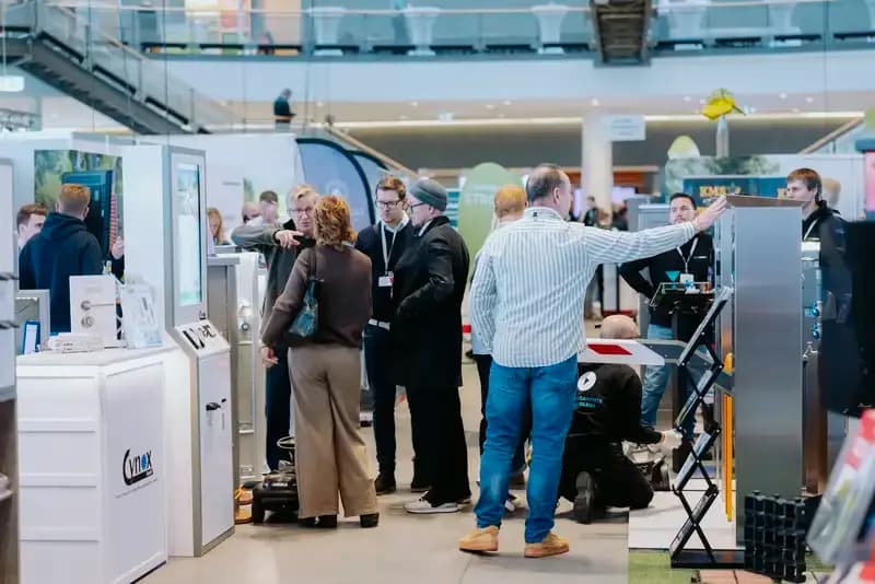 Besucher zwischen Ausstellungsständen mit Sanitär- und Technikmustern in einer Messehalle
